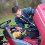 Mechanic working on old riding mower battery